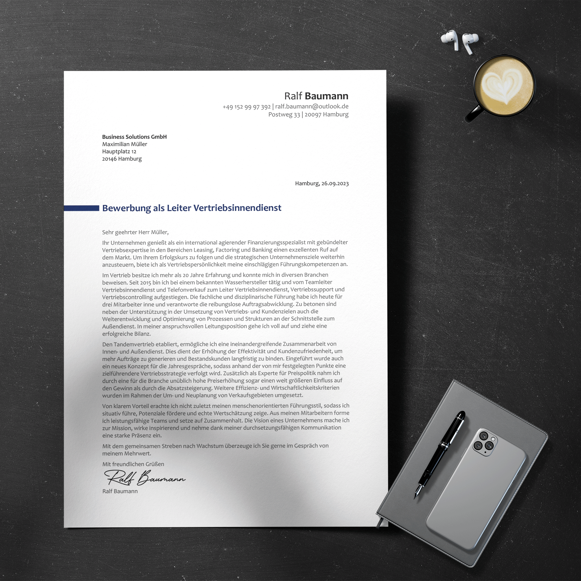 Auf einem Schreibtisch liegt ein „Anschreiben Manager“ mit Smartphone, Stift und Kaffee mit Latte Art. Es ist an ein Hamburger Unternehmen adressiert und stellt eine Bewerbung für die Position Vertriebsleitung dar. Kontaktdaten und Unterschrift sind zu sehen.