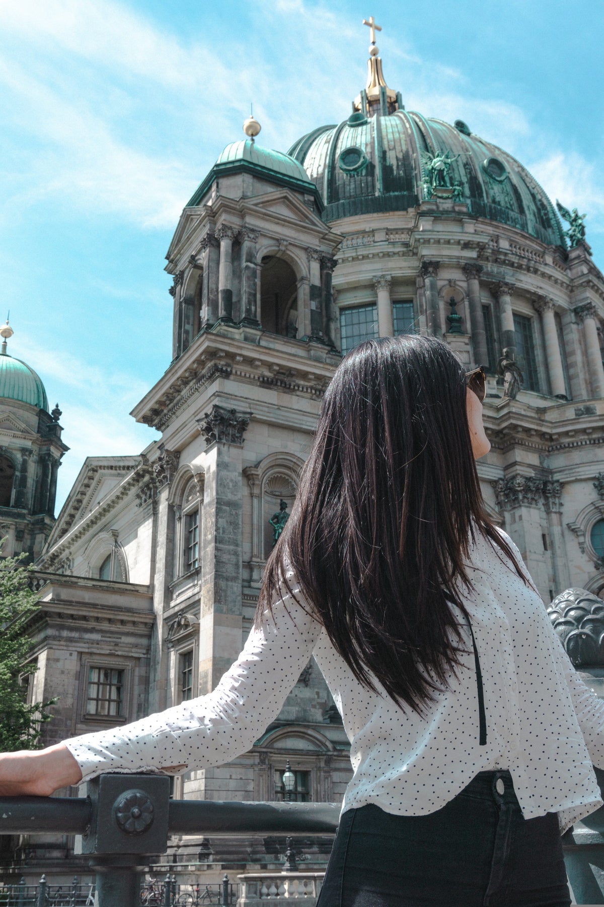 Frau mit langen dunklen Haaren am Spreeufer, im Hintergrund die Kuppel des Berliner Doms